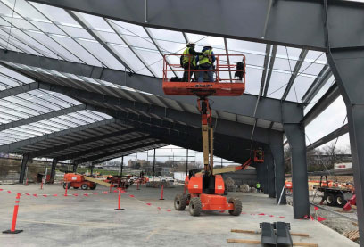 Two construction workers on lift surveying steel erection of building